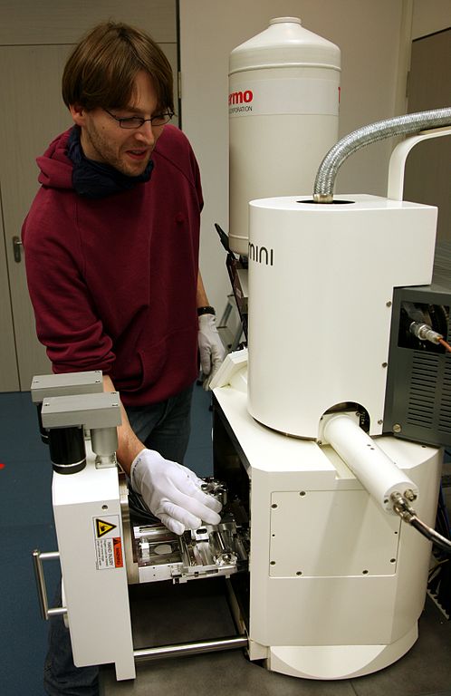 A person loading a sample into a scanning electron microscope, image by Daniel Schwen.